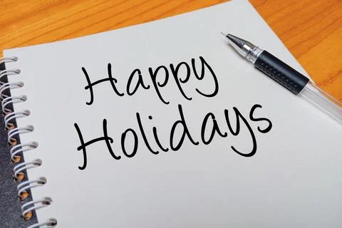 Top view of an open spiral notebook with Happy Holidays handwritten text ov.. Stock Photos