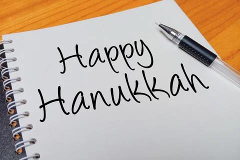 Top view of an open spiral notebook with Happy Hanukkah handwritten text ov.. Stock Photos
