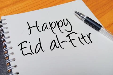 Top view of an open spiral notebook with Happy Eid al-Fitr handwritten text.. Stock Photos