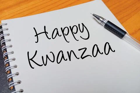 Top view of an open spiral notebook with Happy Kwanzaa handwritten text ove.. Stock Photos