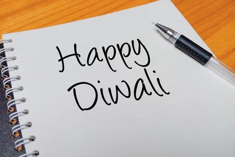 Top view of an open spiral notebook with Happy Diwali handwritten text over.. Stock Photos