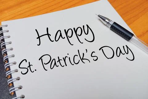Top view of an open spiral notebook with Happy St. Patrick's Day handwritte.. Stock Photos