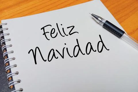 Top view of an open spiral notebook with Feliz Navidad handwritten text ove.. Stock Photos