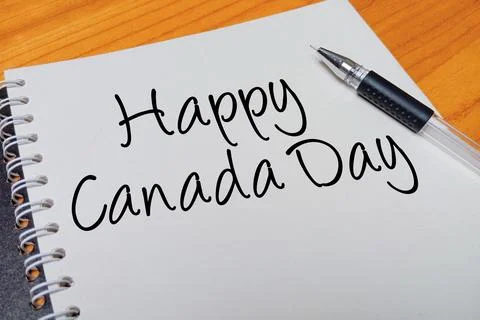 Top view of an open spiral notebook with Happy Canada Day handwritten text .. Stock Photos