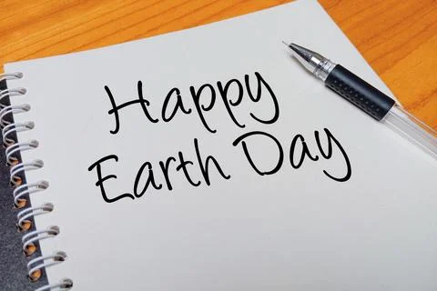 Top view of an open spiral notebook with Happy Earth Day handwritten text o.. Stock Photos