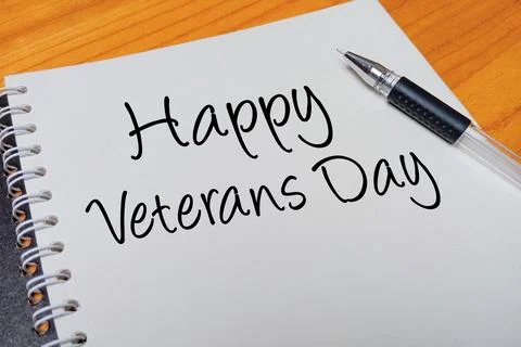 Top view of an open spiral notebook with Happy Veterans Day handwritten tex.. Stock Photos