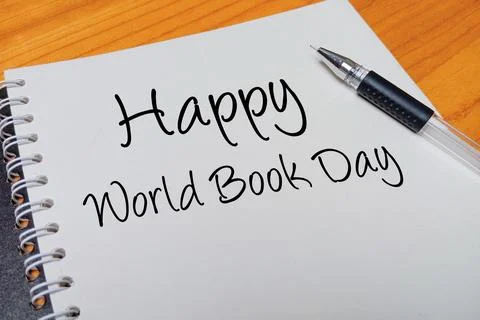 Top view of an open spiral notebook with Happy World Book Day handwritten t.. Stock Photos