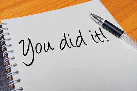 Top view of an open spiral notebook with You did it! handwritten text overl.. Stock Photos