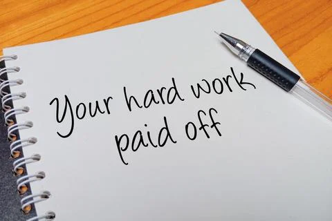 Top view of an open spiral notebook with Your hard work paid off handwritte.. Stock Photos