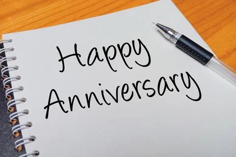 Top view of an open spiral notebook with Happy Anniversary handwritten text.. Stock Photos