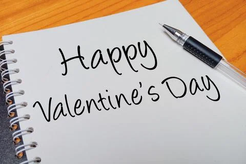 Top view of an open spiral notebook with Happy Valentine's Day handwritten .. Stock Photos