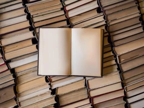 Top view of an opened book over lot of books. Wisdom and knowledge concept Stock Photos