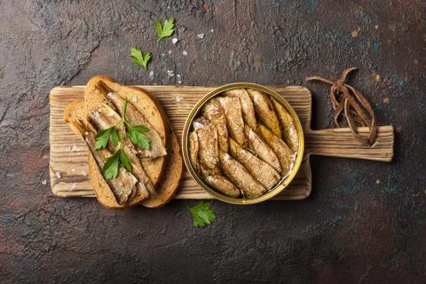 Top view of opened can with fish in oil and sandwich with smoked sprats, pars Stock Photos