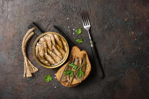Top view of opened can with fish in oil and sandwich with smoked sprats, pars Stock Photos