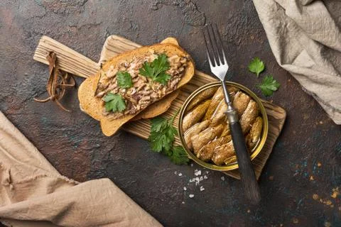 Top view of opened can with fish in oil and sandwich with smoked sprats, pars Stock Photos