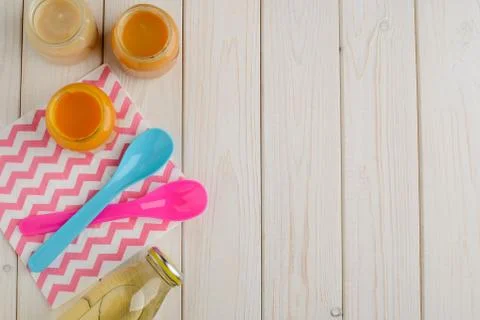 Top view on opened jars of assorted purees, bottle of juice and spoons Stock Photos