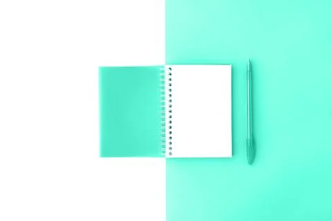 Top view of opened trendy mint cover spiral notepad with pen on mint and white Foto stock