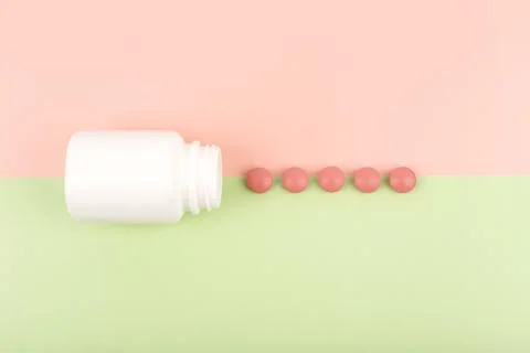 Top view of an opened white medication bottle with spilled red round pills on Stock Photos