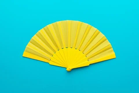 Top view of opened yellow hand fan on turquoise blue background with copy space Stock Photos