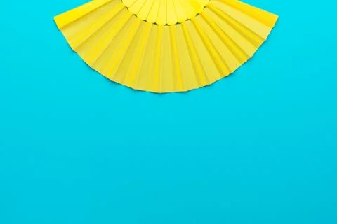 Top view of opened yellow hand fan on turquoise blue background with copy space Stock Photos