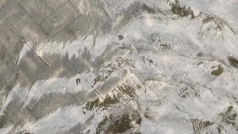 Top view or flat lay view of shallow water flow on grey paved background Stock Footage 293784174