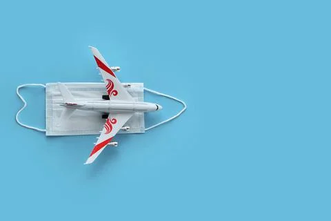 Top view or flat lay of airplane model and medical face mask on blue background. Foto stock