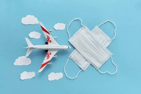 Top view or flat lay of airplane model and medical face mask on blue backgrou Stock Photos
