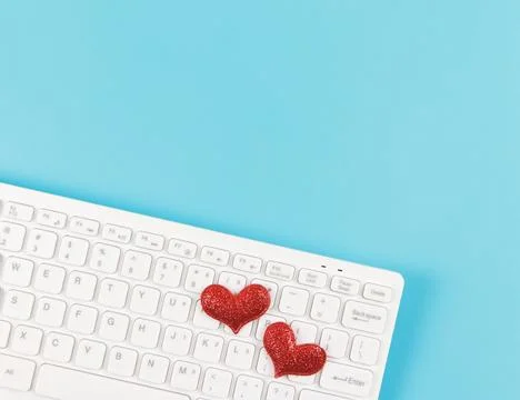 Top view or flat lay of  two red glitter hearts  on white computer keyboard o Stock Photos