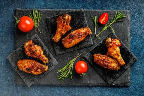 Top view or flatlay concept with grilled, roasted hicken wings on a black stone Stock Photos