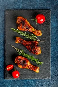 Top view or flatlay concept with grilled, roasted hicken legs on a black stone Stock Photos