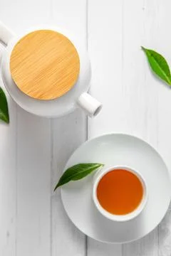 Top view or flatlay with herbal tea in a cup and teapot on white wooden Foto stock