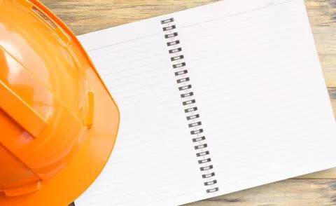 Top view with orange safety engineer helmet and notebook on wood table Foto stock