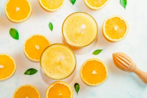 Top view of orange smoothie and orange fruits with green leaves on white back Stock Photos