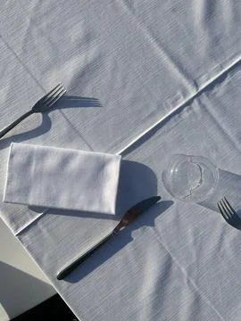 Top view of outdoors table setting with white linen tablecloth cutlery. Stock Photos
