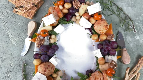 Top view of an oval ceramic plate with sausage, cheese and vegetable appetizers  Vídeos de archivo 304458779