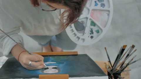 Top view of painter in front of an easel and painting painting altarpiece Stock Footage 130617982