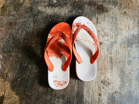 Top view of a pair of worn flip flops lying on a rough concrete floor. Foto stock