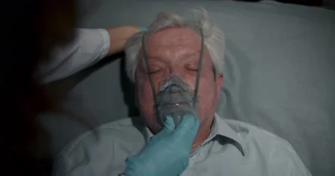 Top view of paramedic putting oxygen mask on unconscious senior man patient in Stock Footage 148985112