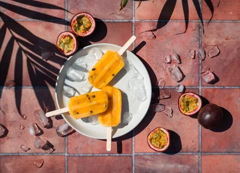 Top view passion fruit popsicles on terra cotta tile in sun. Stock Photos