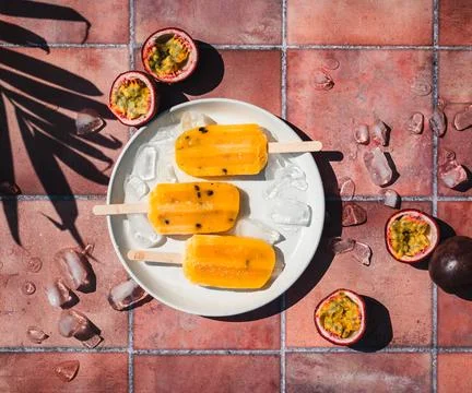 Top view passion fruit popsicles on terra cotta tile in sun. Stock Photos
