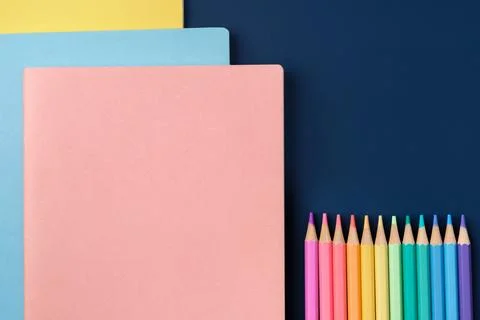 Top view pastel notebook with pencil and stationery on navy blue table back.. Stock Photos