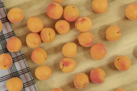 Top view of pattern of apricots on plaid cloth and on wooden background Stock Photos