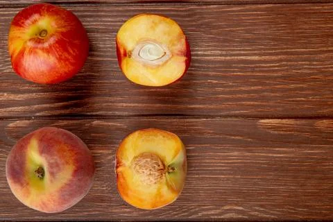 Top view of pattern of whole and half cut peaches on wooden background with.. Stock Photos