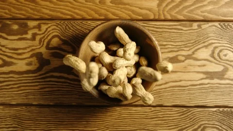 TOP VIEW: Peanuts fall into wooden cup - Slow motion Stock Footage 96193091