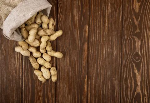 Top view of peanuts in shell scattered from a sack on wooden background wit.. Stock Photos