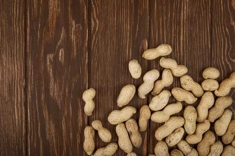 Top view of peanuts in shell scattered on wooden background with copy space Stock Photos