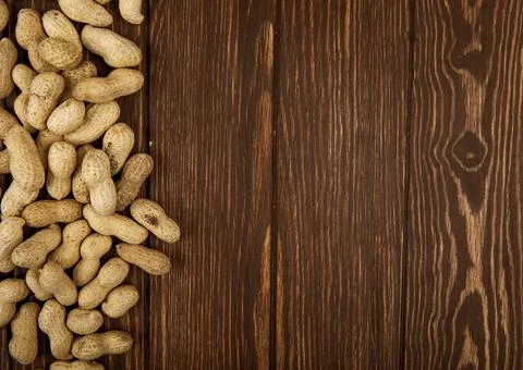 Top view of peanuts in shell scattered on wooden background with copy space Stock Photos