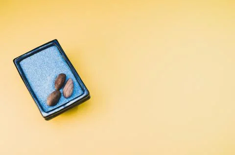 A top view of pebbles on a rectangular box filled with small blue rocks on ye 스톡 사진