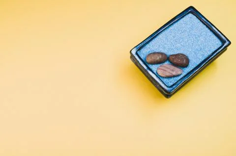 A top view of pebbles on a rectangular box filled with small blue rocks on ye Stockfoto's