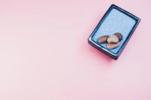 A top view of pebbles on a rectangular box filled with small blue rocks on pi Stock Photos